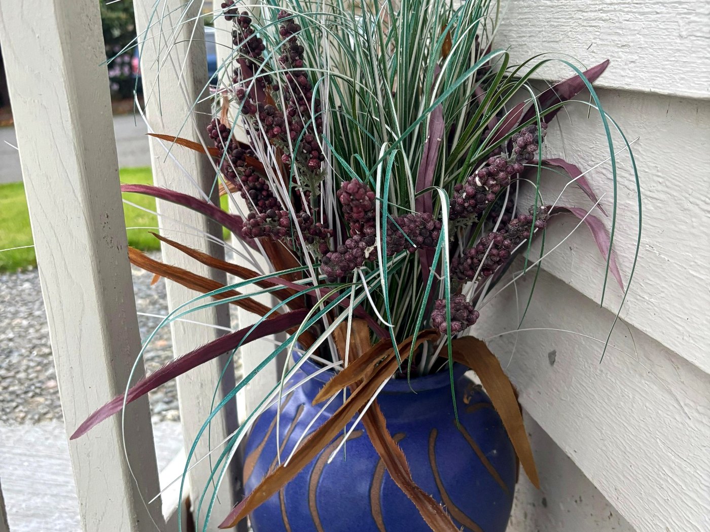 Tall ornamental grasses in a blue glazed pot beside the porch